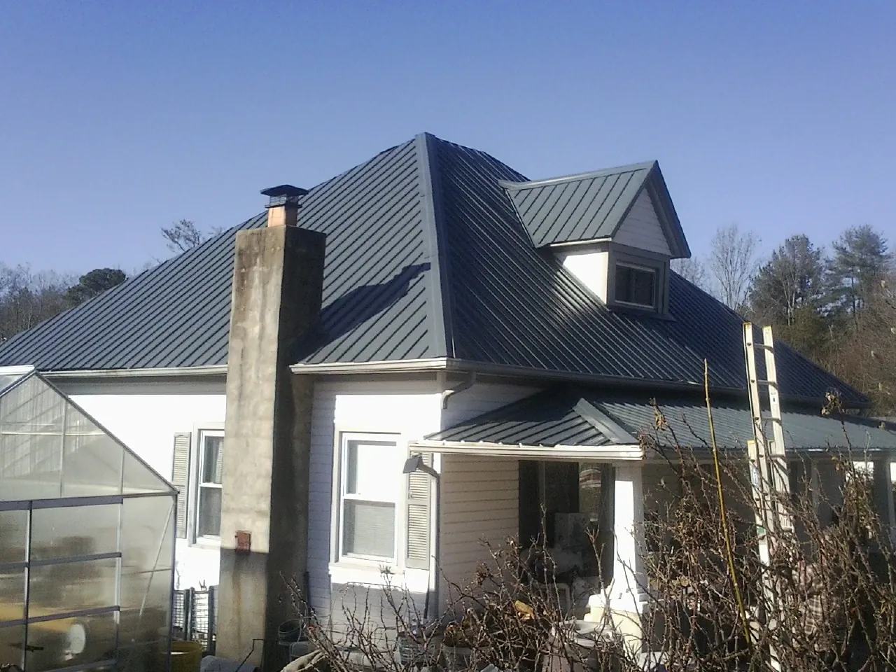 Dark blue standing seam metal roof on a white farmhouse with dormer — Slate & Tile Roof Repair by Roofing Brothers in Leighton