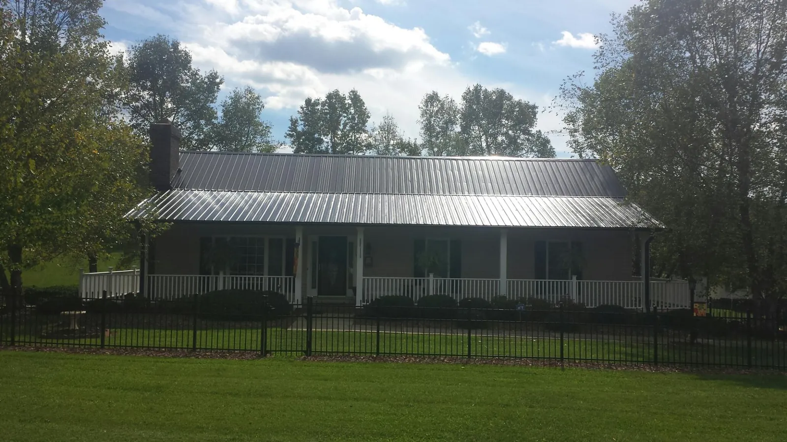 Gray metal roof on a brick ranch with a full width front porch — Gutter Guard Installation work by our crew in Leighton