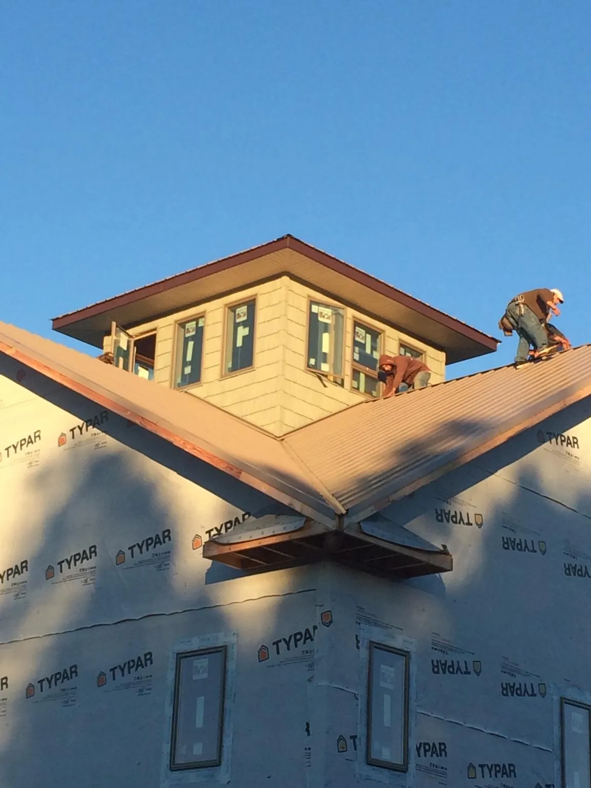 Roofers working around a rooftop cupola on a new metal roof at sunset — Roof Waterproofing in Leighton by Roofing Brothers